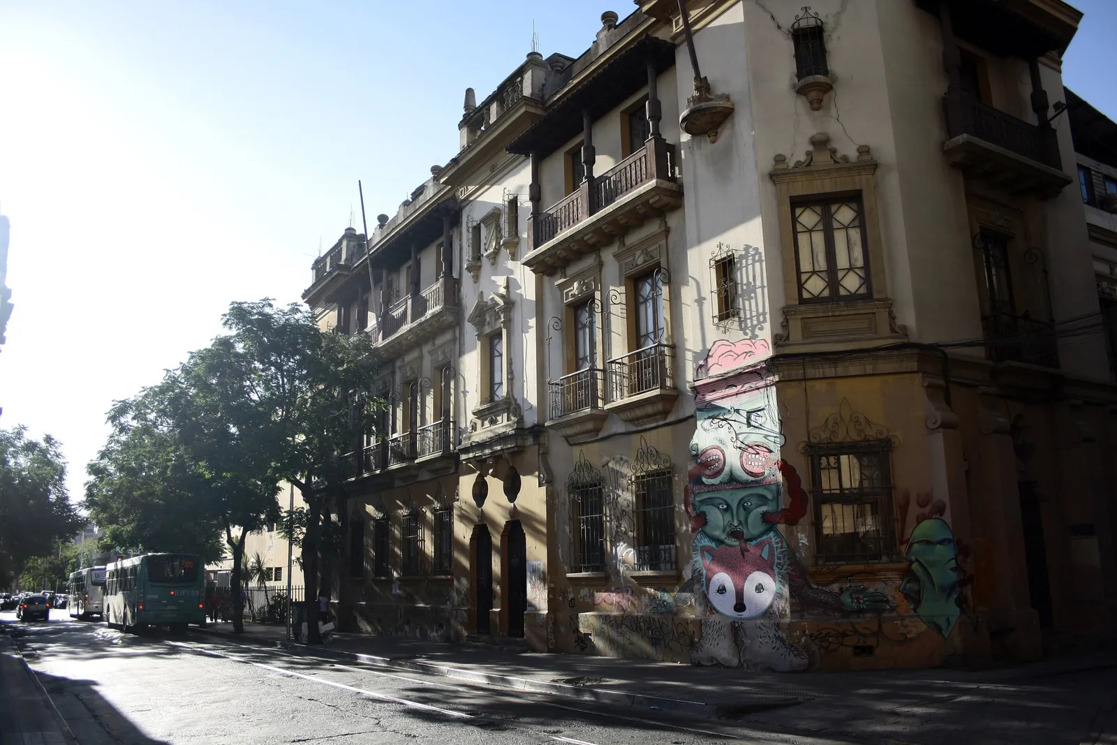 Fachadas antiguas de dos pisos en una calle del Barrio Brasil, con murales pintados en los muros de la planta baja.