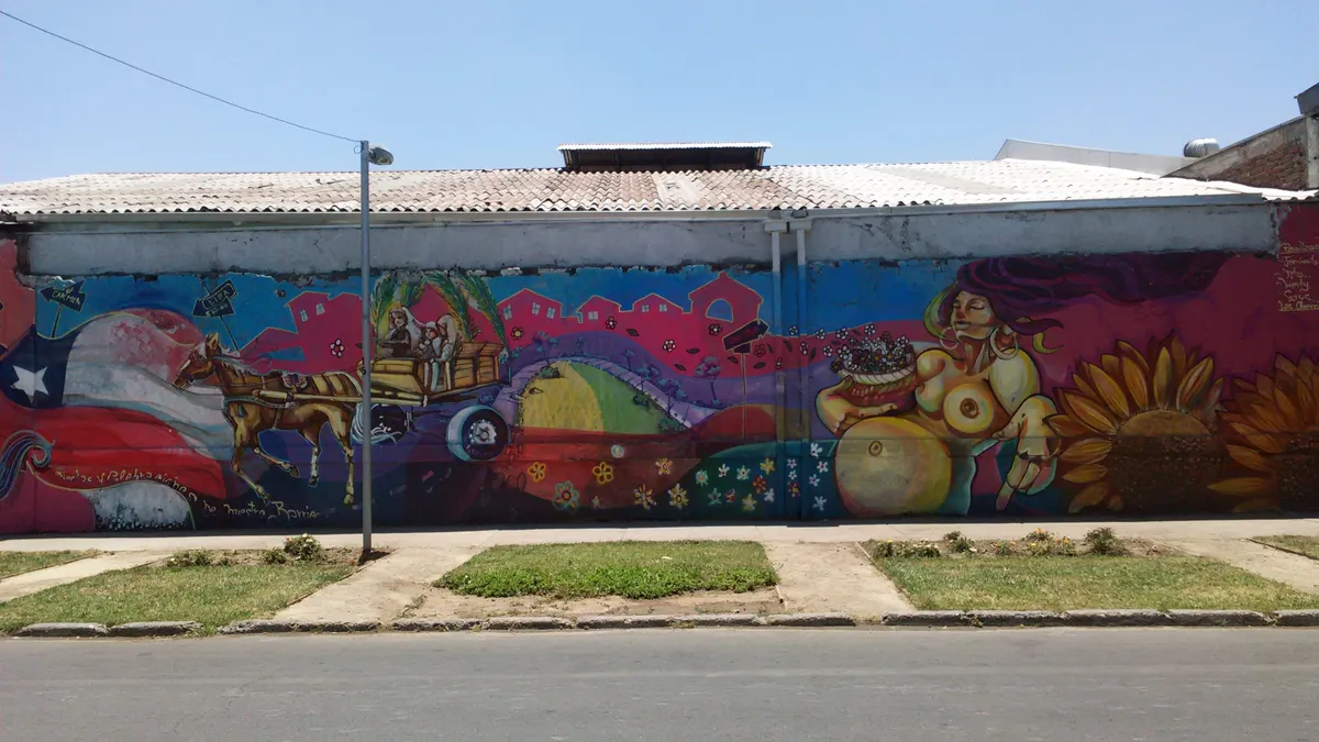 Mural de colores que cubre por completo el muro de un galpón en el Barrio Franklin, visto desde la vereda del frente.