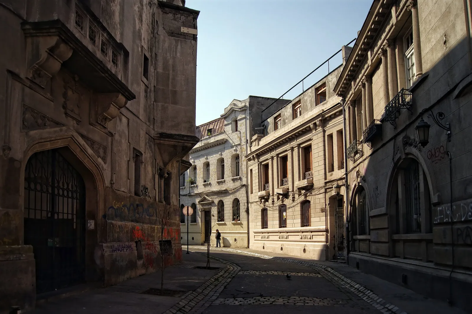 Calle adoquinada y estrecha del Barrio Concha y Toro, entre fachadas de piedra en sombra.
